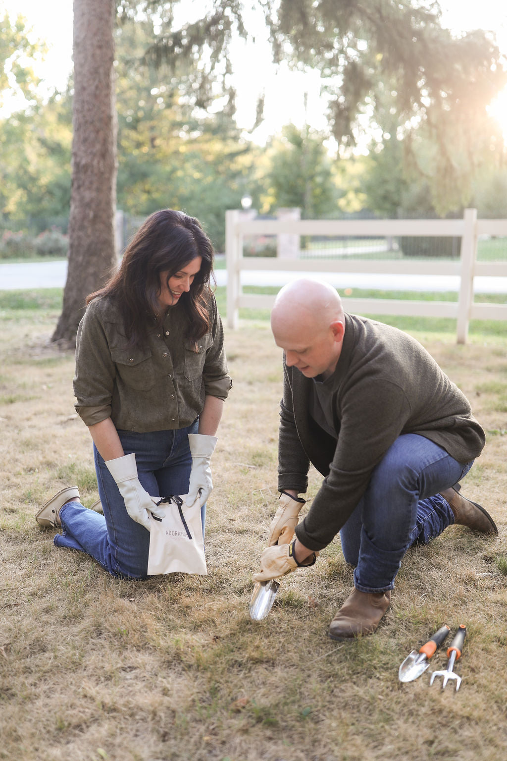 Two people planting peony root in the ground