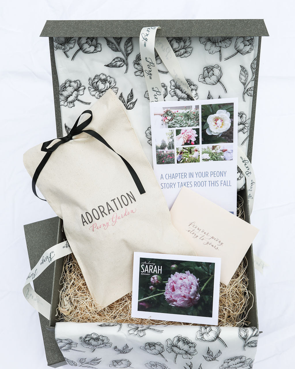 A gift boxes featuring a photo of a pink Sarah Bernhardt peony with an Adoration Peony Garden cotton root pouch